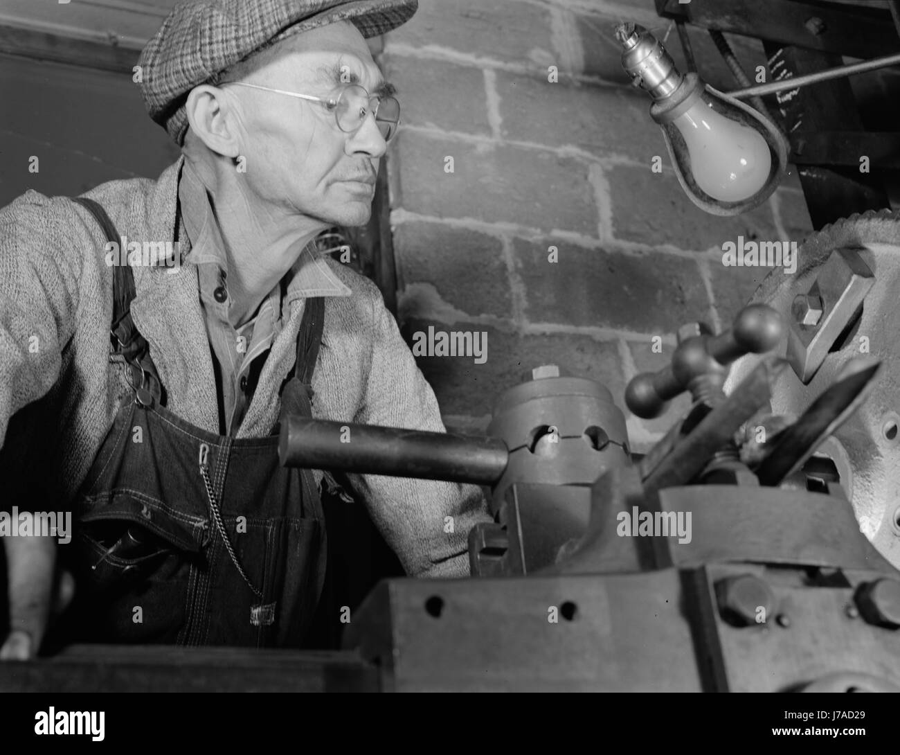 Man working in a small machine shop for war production, circa 1942. Stock Photo