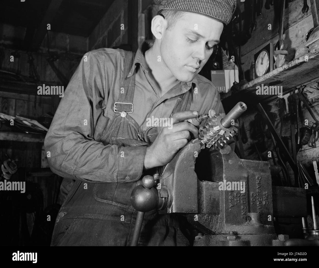Man working in a small machine shop for war production, circa 1942. Stock Photo