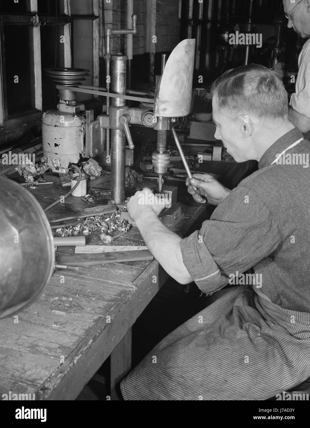 Man operating a drill press making vital parts for war production, 1942. Stock Photo