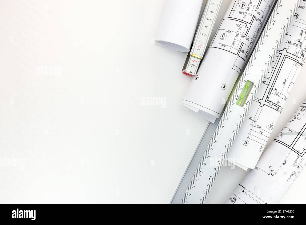 rolls of architectural blueprints, spirit level and zigzag ruler on white background Stock Photo