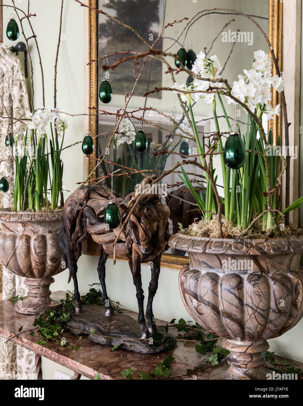 Pair of urns filled with paperwhites (Narcissus papyraceus), twigs and glass ornaments on wrought iron French console table with marble top Stock Photo