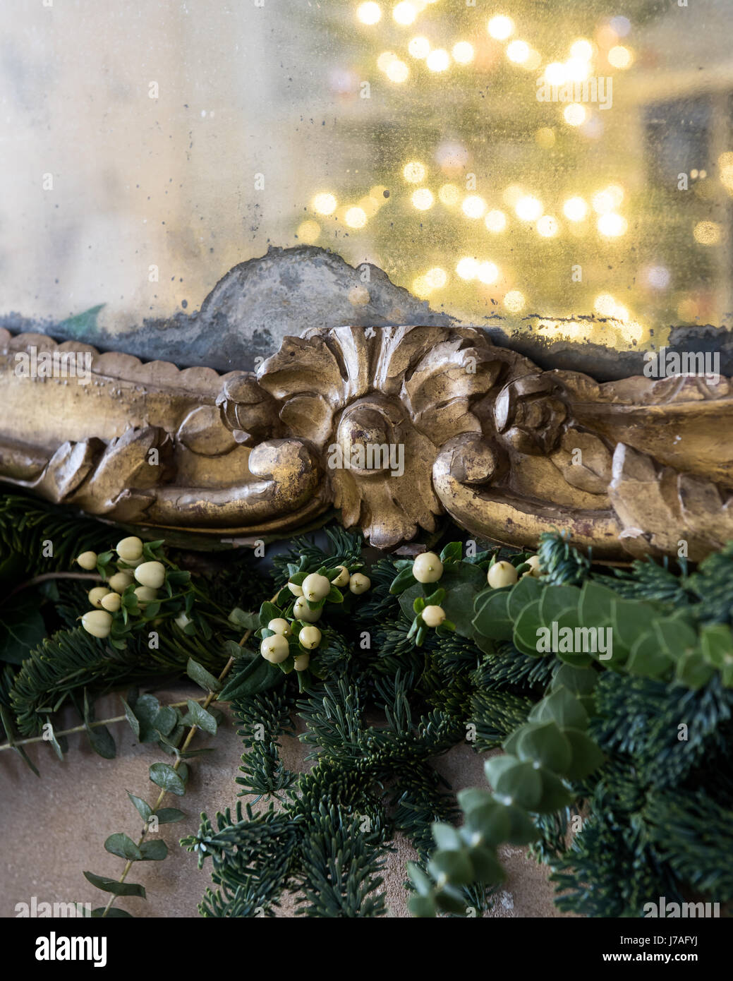 Detail of a flower mould on a gilt framed mirror with eucalyptus and white berries beneath Stock Photo