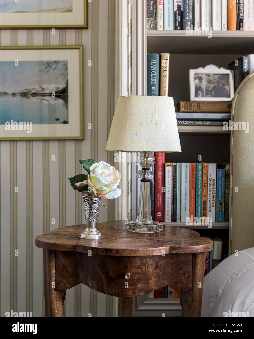 A lamp from Valerie Wade on an antique burr walnut table. The striped fabric lining the walls is by Nicole Fabre. Stock Photo