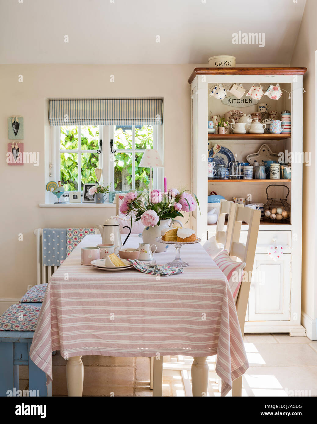 Striped table cloth in pretty country kitchen with ticking stripe blinds by Ian Mankin Stock Photo