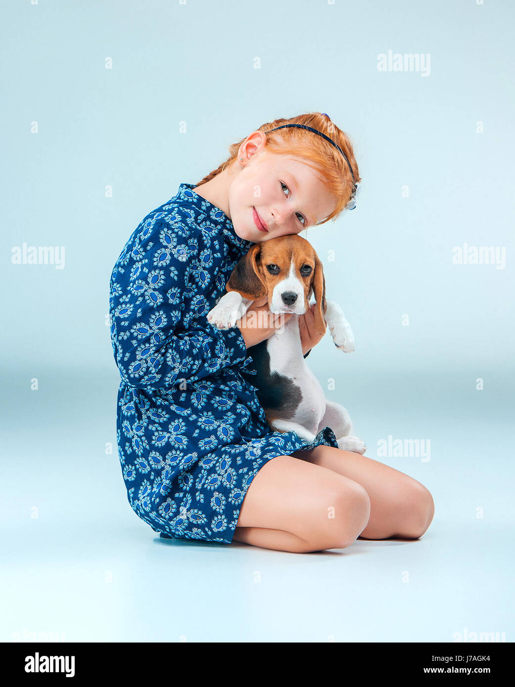 The happy girl and a beagle puppie on gray background Stock Photo