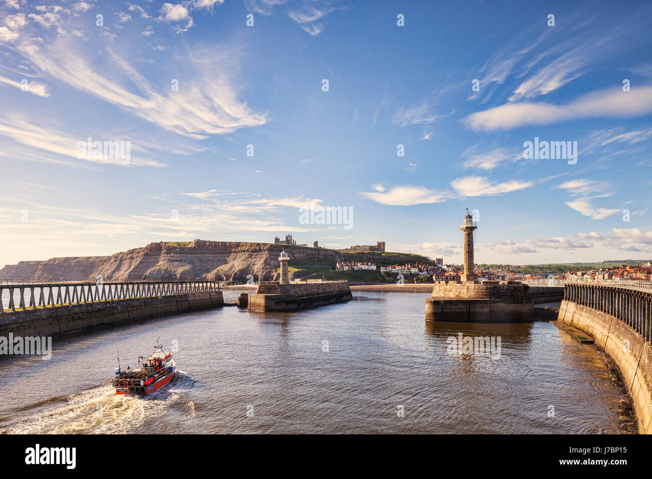 Fishing boat approaching the entrance to the harbour of old fishing port of Whitby, North Yorkshire, England, UK. Stock Photo
