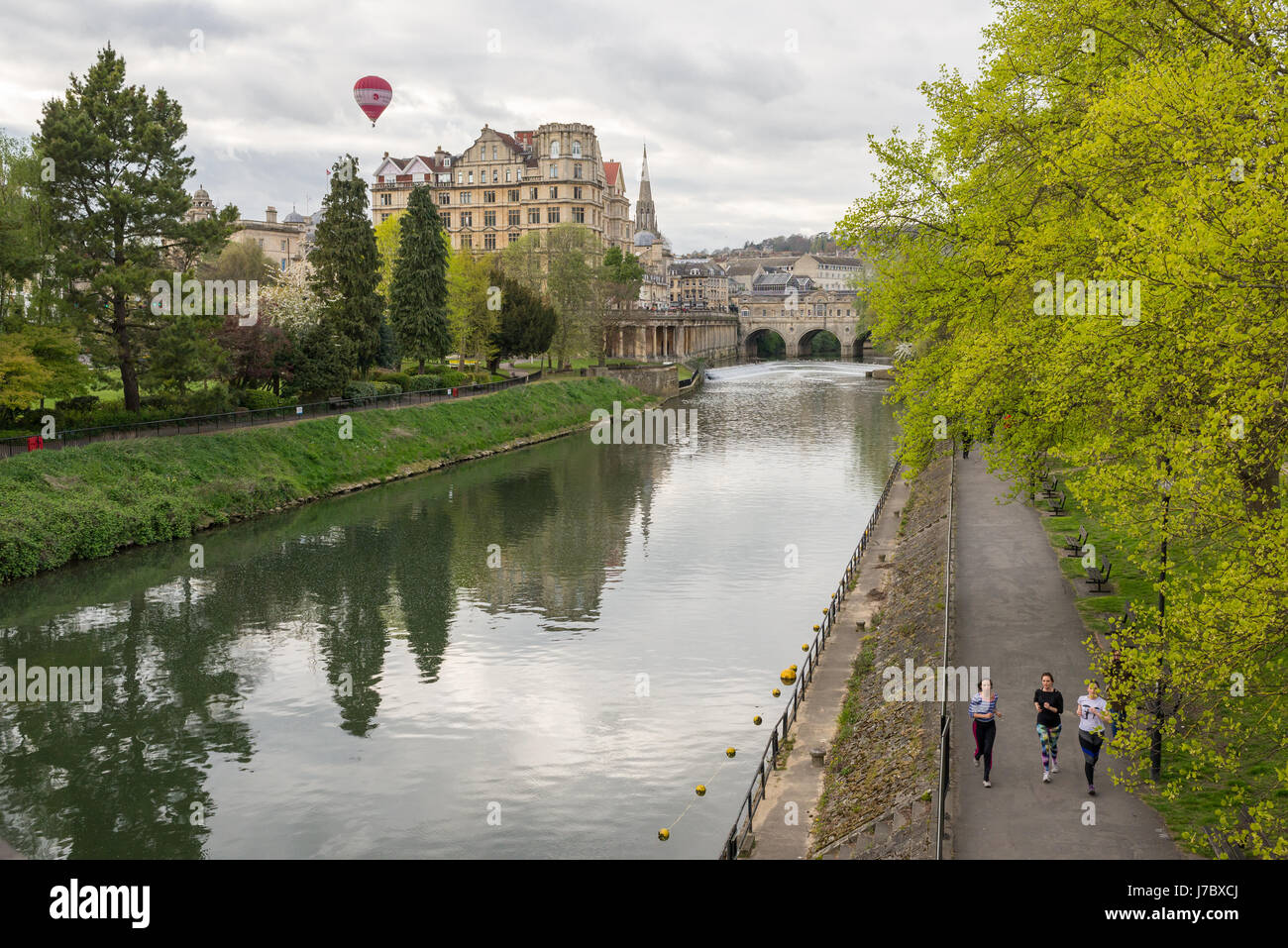 Bath, England - April 2017: Pulteney Bridge crossing the River Avon in Bath, England, UK. Three women running on the footpath along the riverside and  Stock Photo