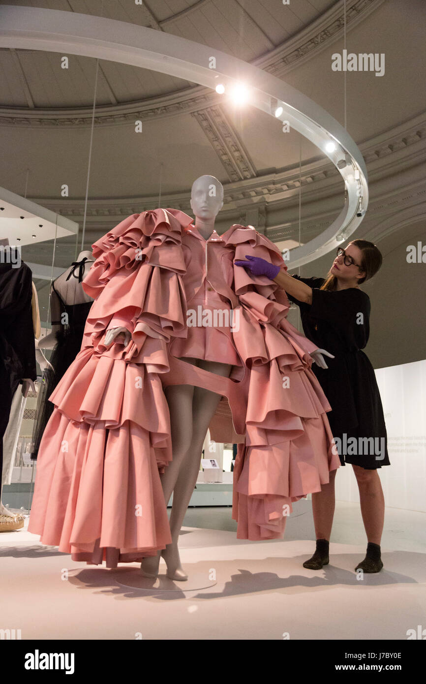 London, UK. 24 May 2017. A museum employee adjusts the Balenciaga-inspired  women's ensemble, polyurethane leather dress by Rei Kawakubo for Comme des  Garcons, Tokyo, 2016. The V&A Museum presents the exhibition Balenciaga: