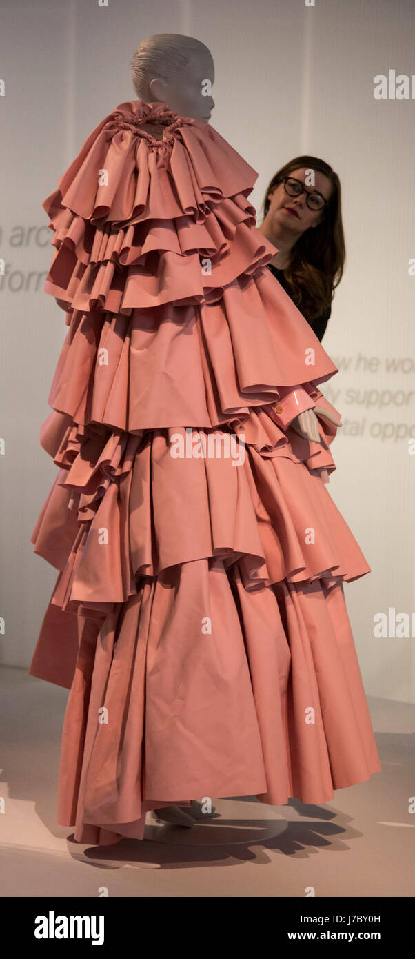 London, UK. 24 May 2017. A museum employee adjusts the Balenciaga-inspired  women's ensemble, polyurethane leather dress by Rei Kawakubo for Comme des  Garcons, Tokyo, 2016. The V&A Museum presents the exhibition Balenciaga: