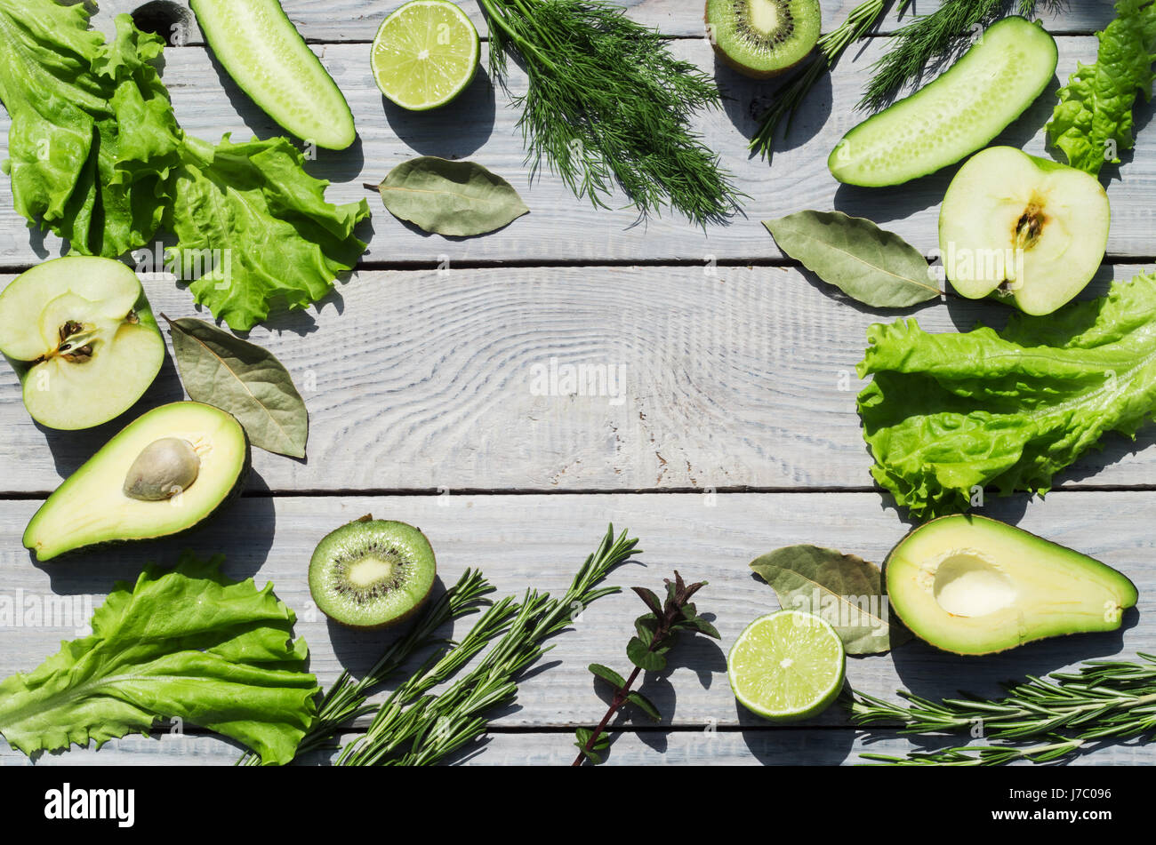 Green fresh vegetables and spices on a white wooden table. Top view ...