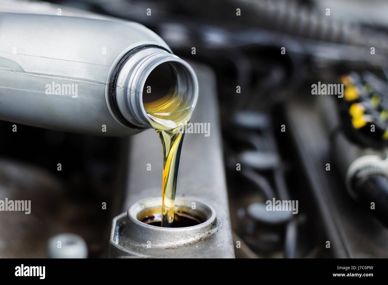 Poured engine oil to the car engine. The mechanic exchanges the oil in