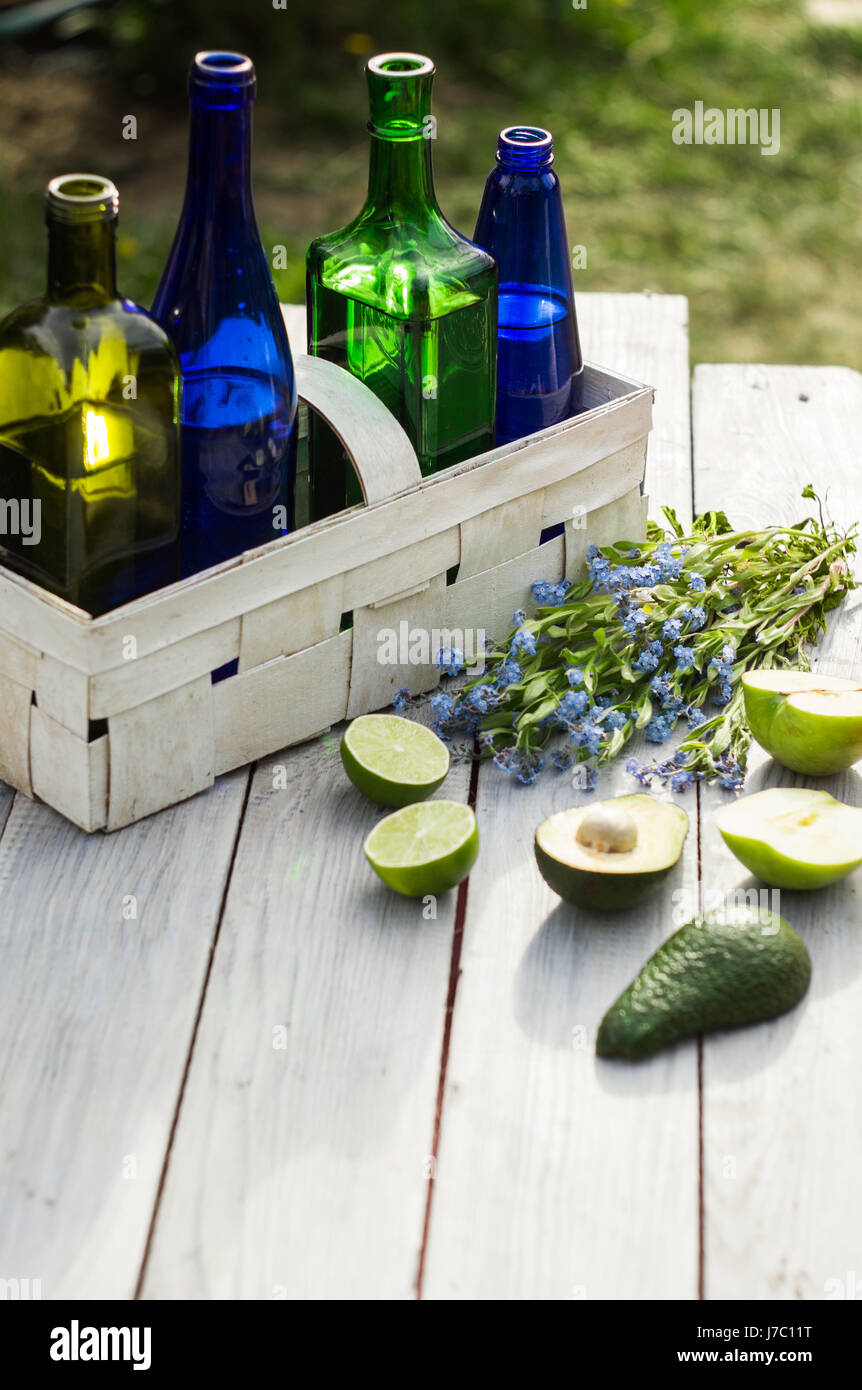 Four bottles of drinks in a white basket and fruits on a white table Stock Photo