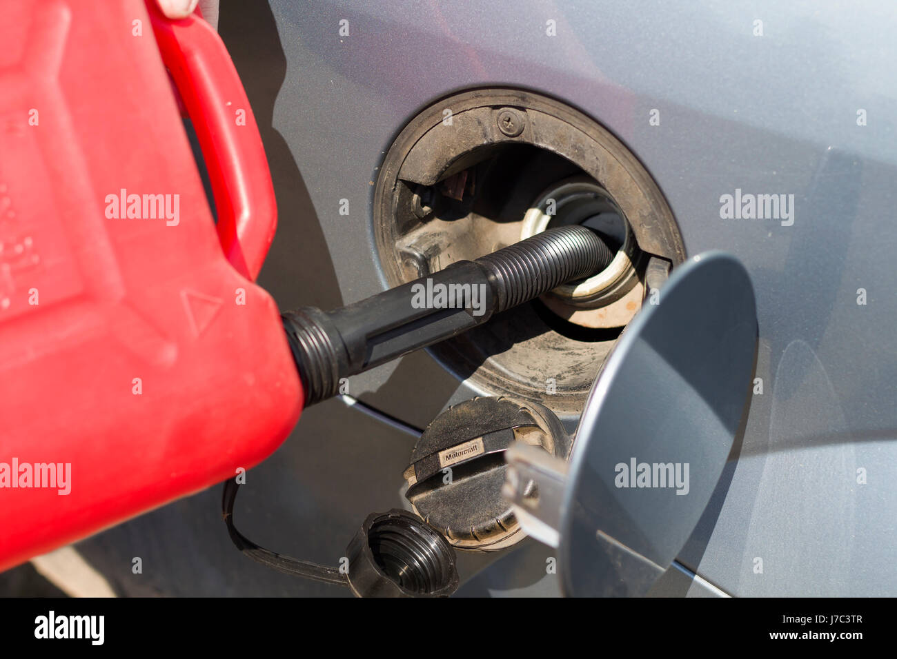 Add fuel from a plastic canister to the car's tank. Refilling fuel from a plastic canister. Car