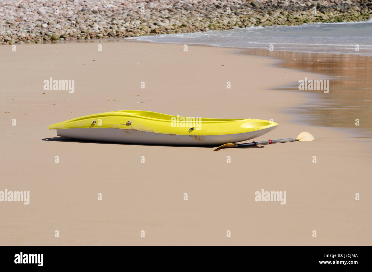 Yellow canoe lying on the beach with no one around. Stock Photo