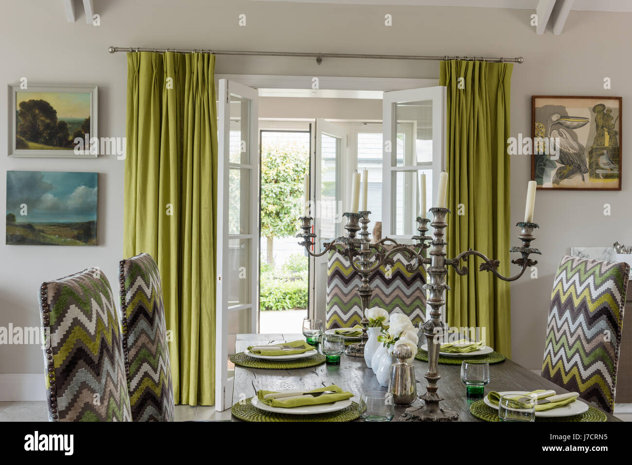 Silver antique candlesticks on dining table with upholstered chairs