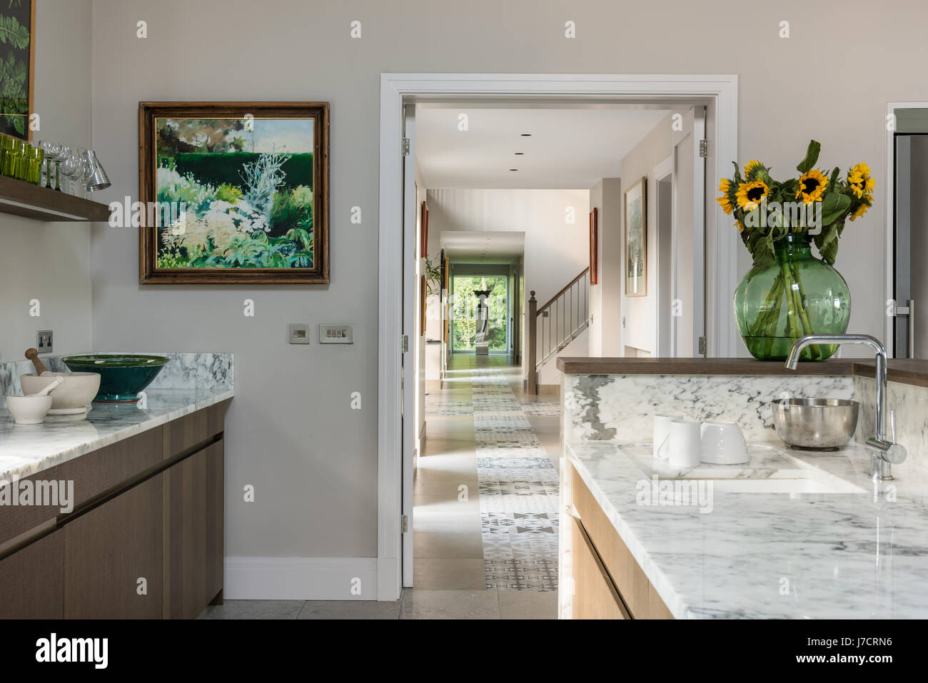 Sunflowers and framed artwork in marble kitchen with view to internal entrance Stock Photo
