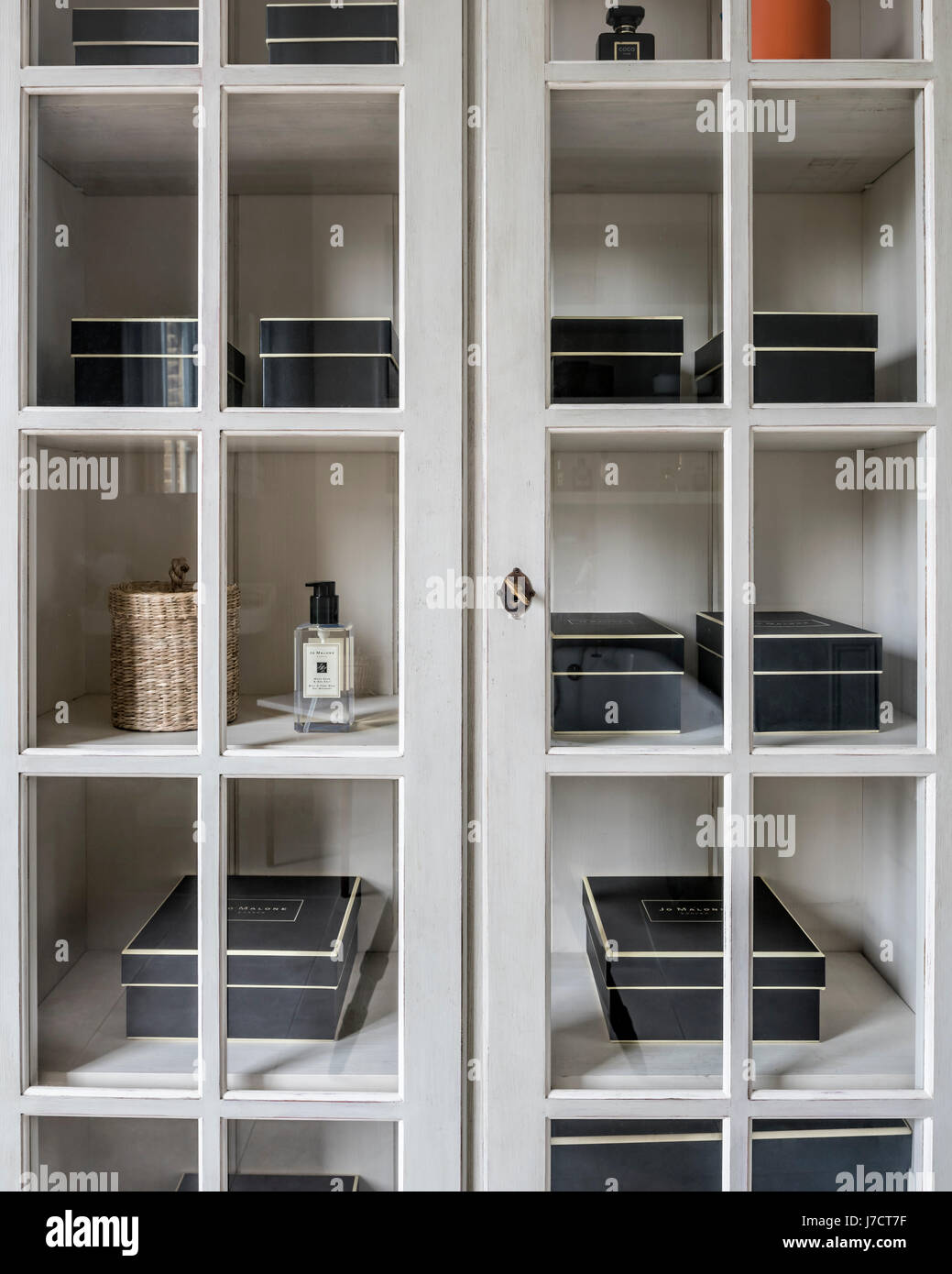 Jo Malone boxes in cupboard with glass fronted panels Stock Photo