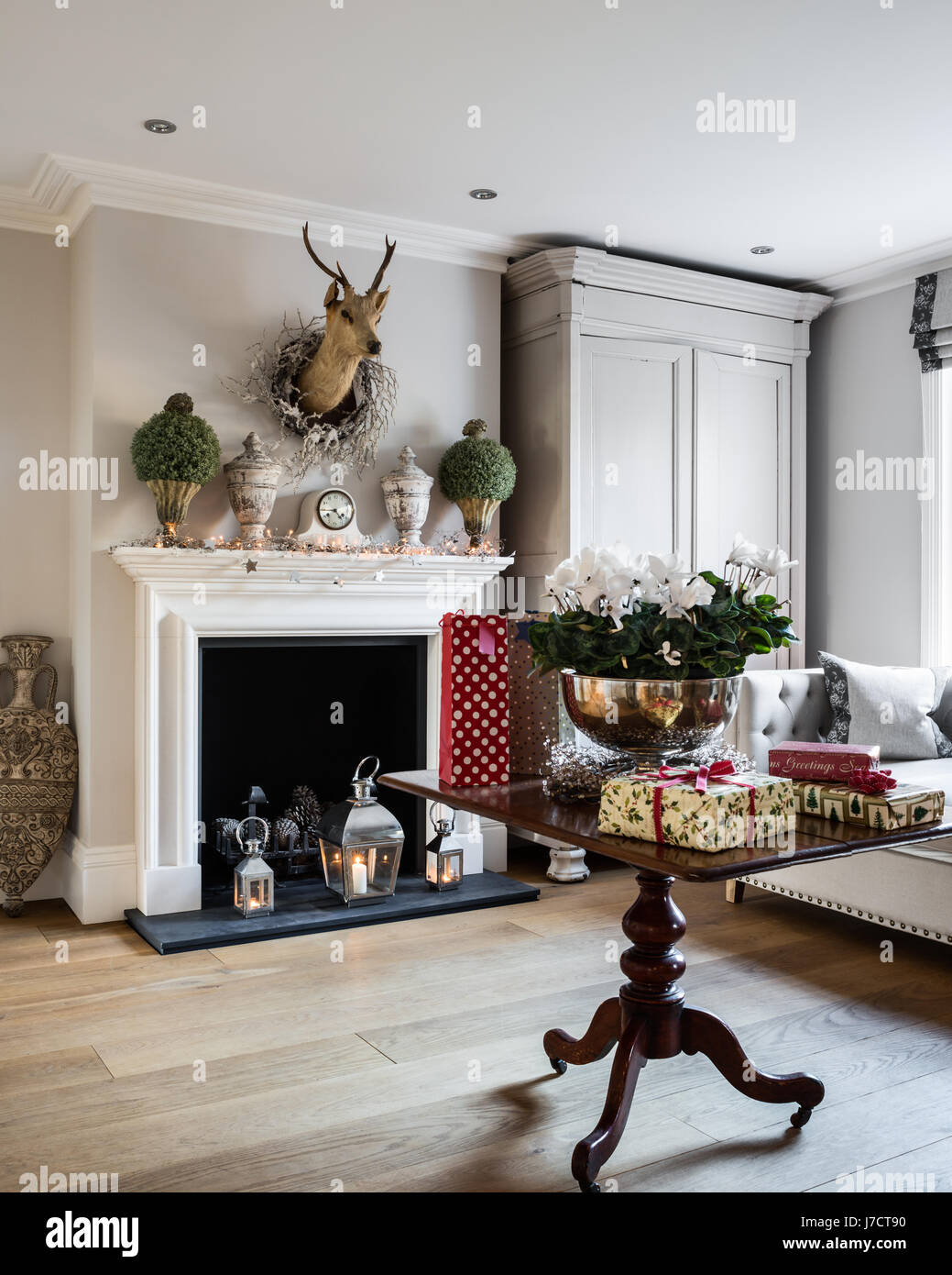 Faux thyme on fireplace in spacious hallway with Christmas gifts on table Stock Photo