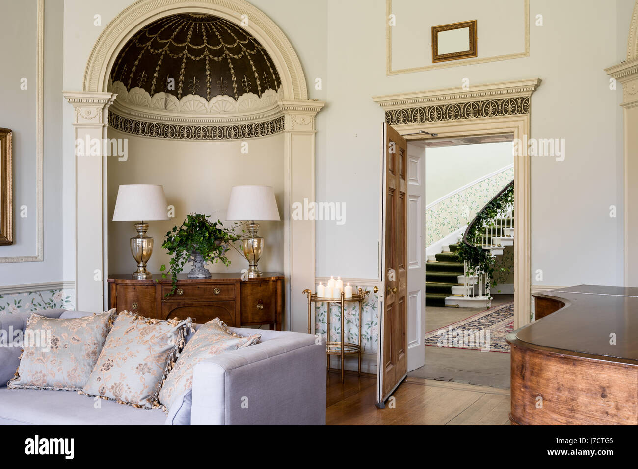 Drawing room with pair of silver lamp stands on sideboard in alcove with georgian gilt decor mouldings. Stock Photo