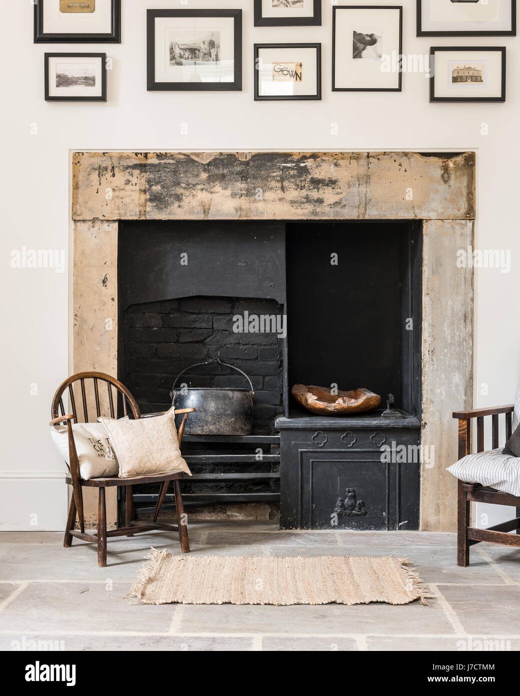 Original fireplace in sitting room with flagstone flooring and old windsor chair Stock Photo