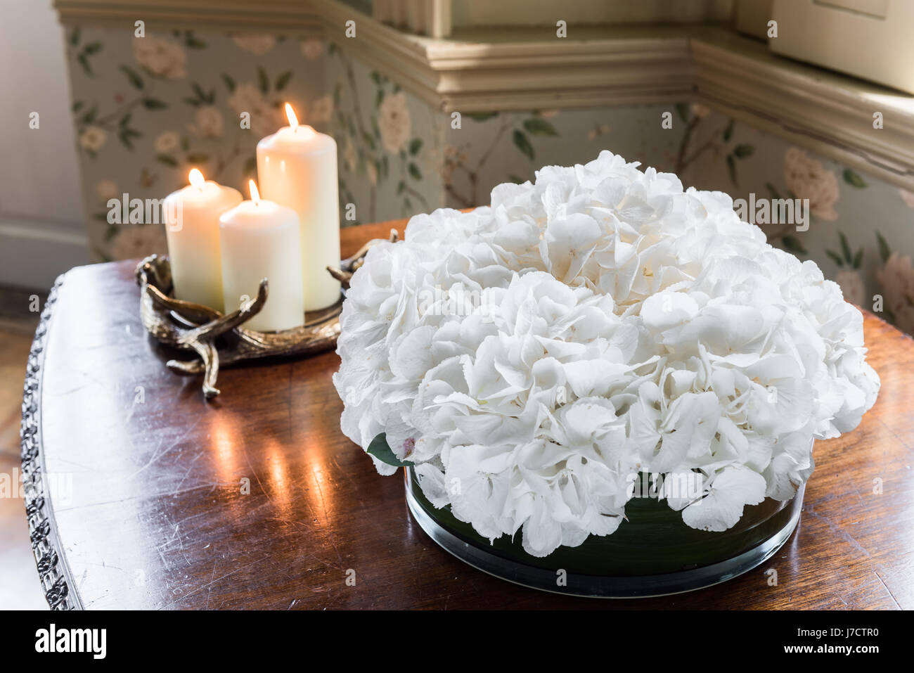 Hydrangeas and candles decorate a side table Stock Photo