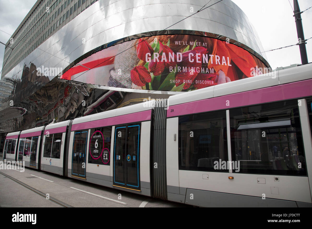 Exterior of Grand Central with a passing Midland Metro light-rail tram in Birmingham, United Kingdom. Grand Central is a shopping centre located in Birmingham, England, that opened on 24 September 2015. It is currently owned by Hammerson and CPPIB. The original centre was built in 1971 as part of the reconstruction of Birmingham New Street station. It was known as the Birmingham Shopping Centre before being renamed as The Pallasades. As part of the New Street Station Gateway Plus redevelopment, Grand Central underwent a major overhaul. The mall has been redesigned with a glass atrium roof as c Stock Photo