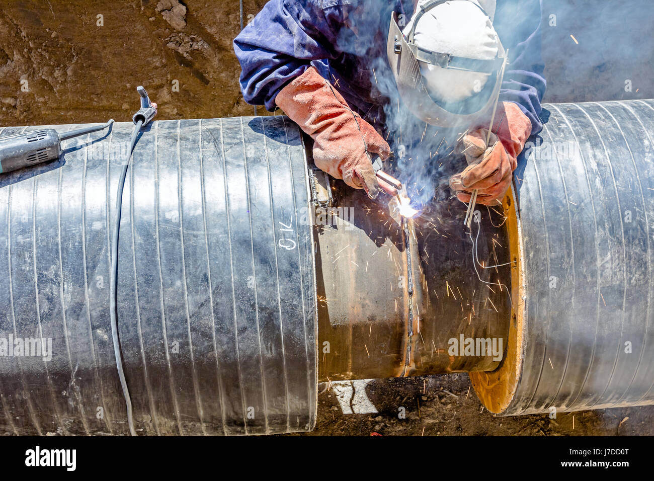 Welder is in trench working hard, arc welding pipeline Stock Photo Alamy