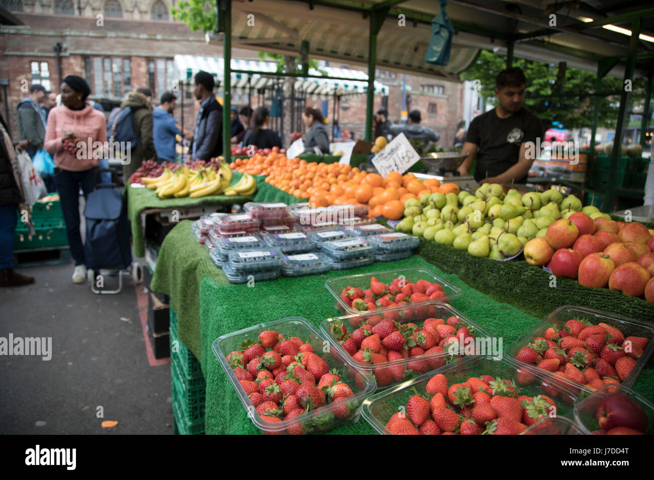 Multicultural scene at the Bullring Open Market, an outdoor food market in central Birmingham, United Kingdom. The Open Market offers a huge variety of fresh fruit and vegetables, fabrics, household items and seasonal goods. The Bull Ring Open Market has 130 stalls. Stock Photo
