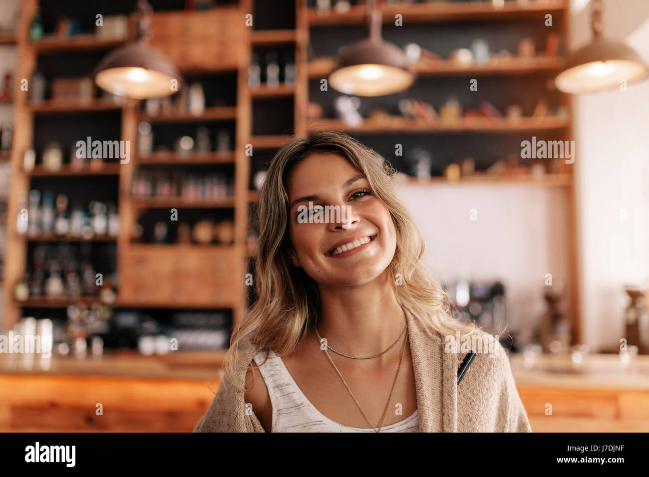 Portrait of beautiful young caucasian woman standing in a cafe looking ...