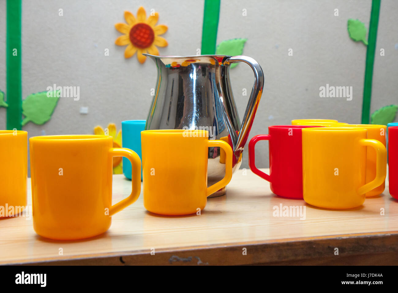 Silver jug and colourful plastic cups stand on a table Stock Photo