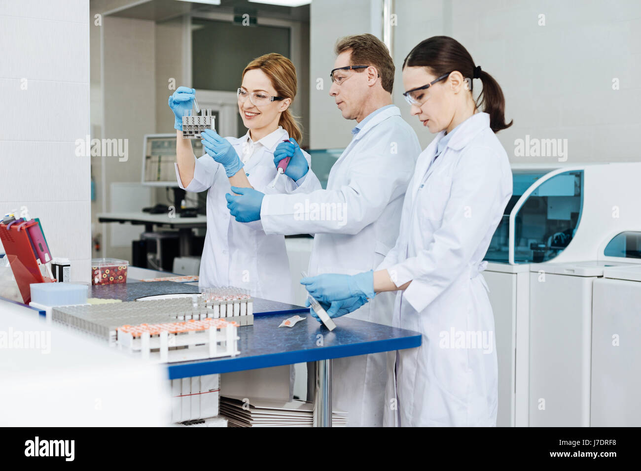 Line of three colleagues working at modern lab Stock Photo