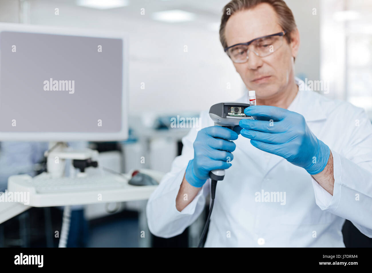 Serious lab assistant looking attentively at test glass Stock Photo