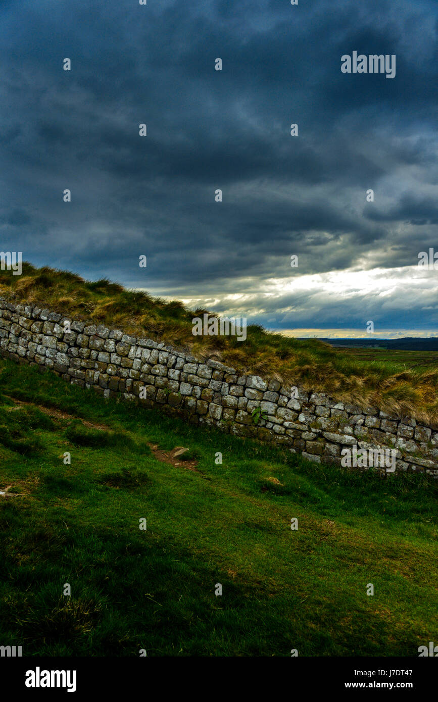 A moody portrait view of a part of Hadrians Wall, in Northumberland, UK. Grey clouds seem to merge with the grey of the stones. Stock Photo