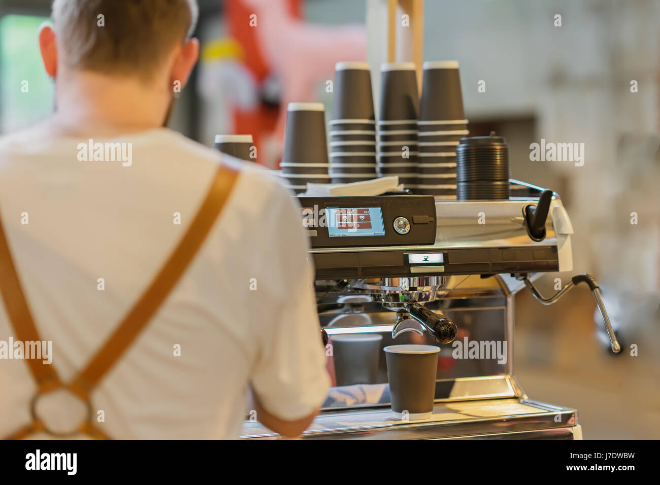 Professional barista preparing coffee in the coffee machine. View from the back. Fresh espresso. Coffee culture, professional making, service and catering concepts Stock Photo
