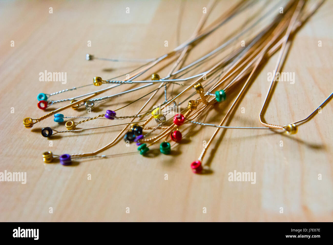 An assortment of used electric guitar strings on a wooden surface left over after replacing several sets of strings. Stock Photo
