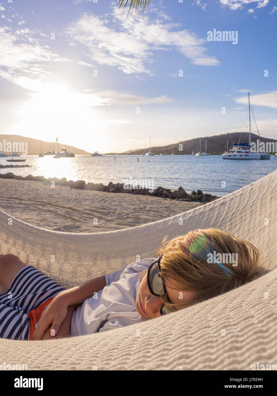 young boy in sunglasses naps in during a vacation in a hammock at the