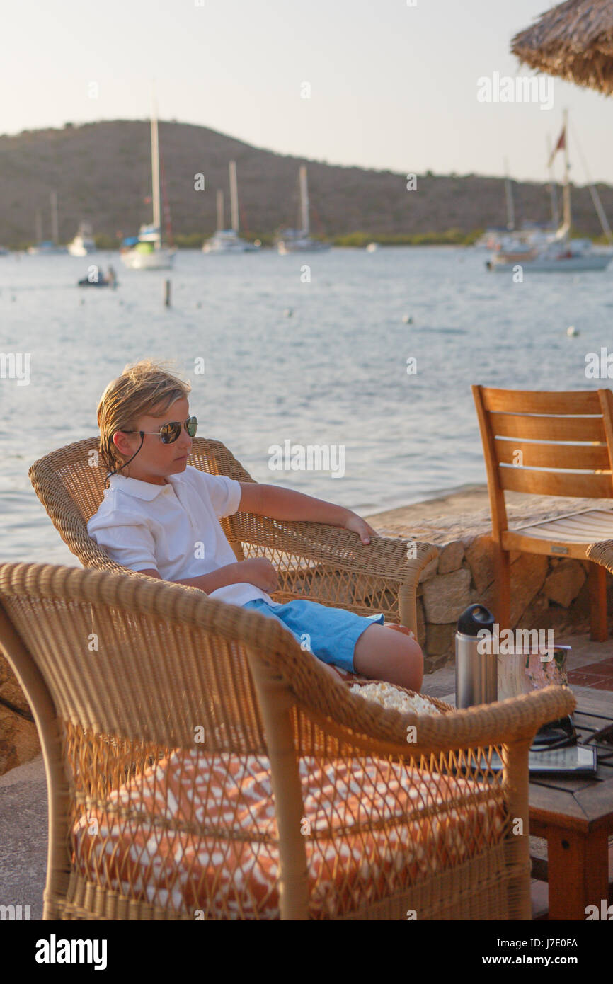 a young boy in sunglasses enjoys cocktails at sunset at the Bitter End