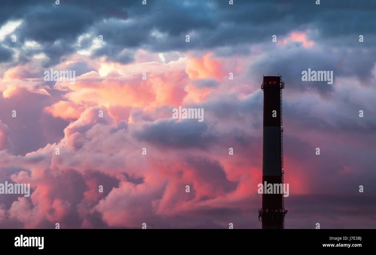 Industrial chimney stack silhouette against the background of the storm sky at sunset Stock Photo