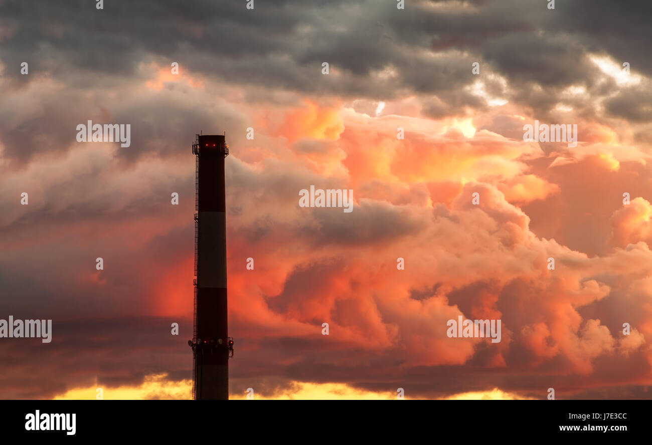 Industrial chimney stack silhouette against the background of the storm sky at sunset Stock Photo