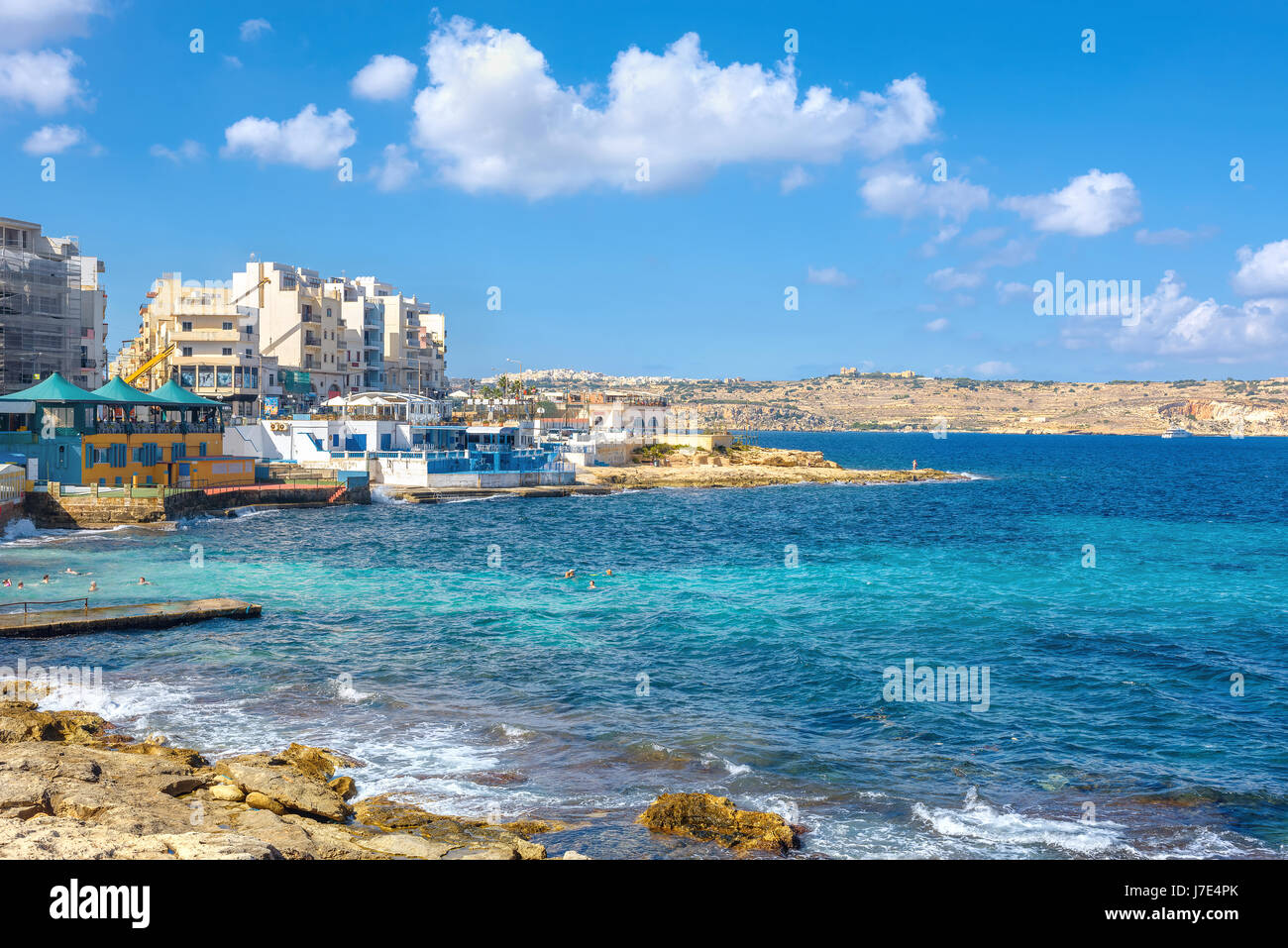 View of stone shore and seaside buildings in Bugibba district. Malta Stock Photo