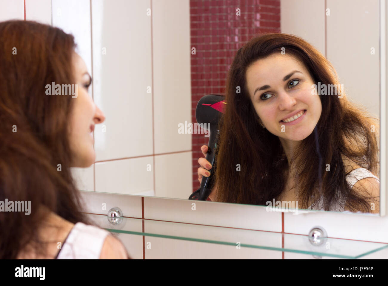 Young woman drying her hair in bathroom Stock Photo - Alamy