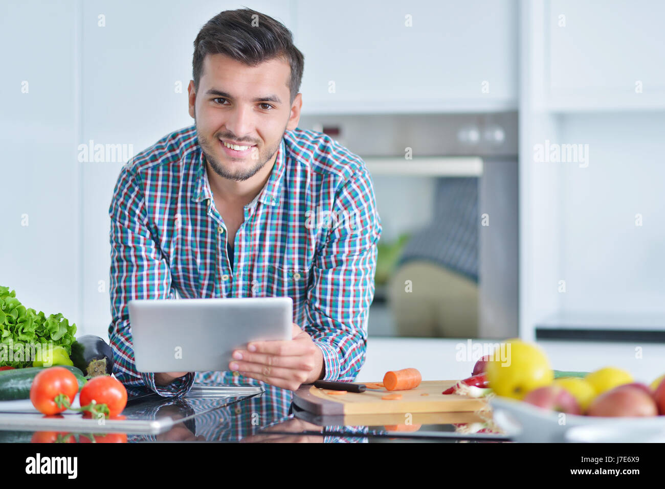 Happy man using digital tablet in kitchen at home Stock Photo