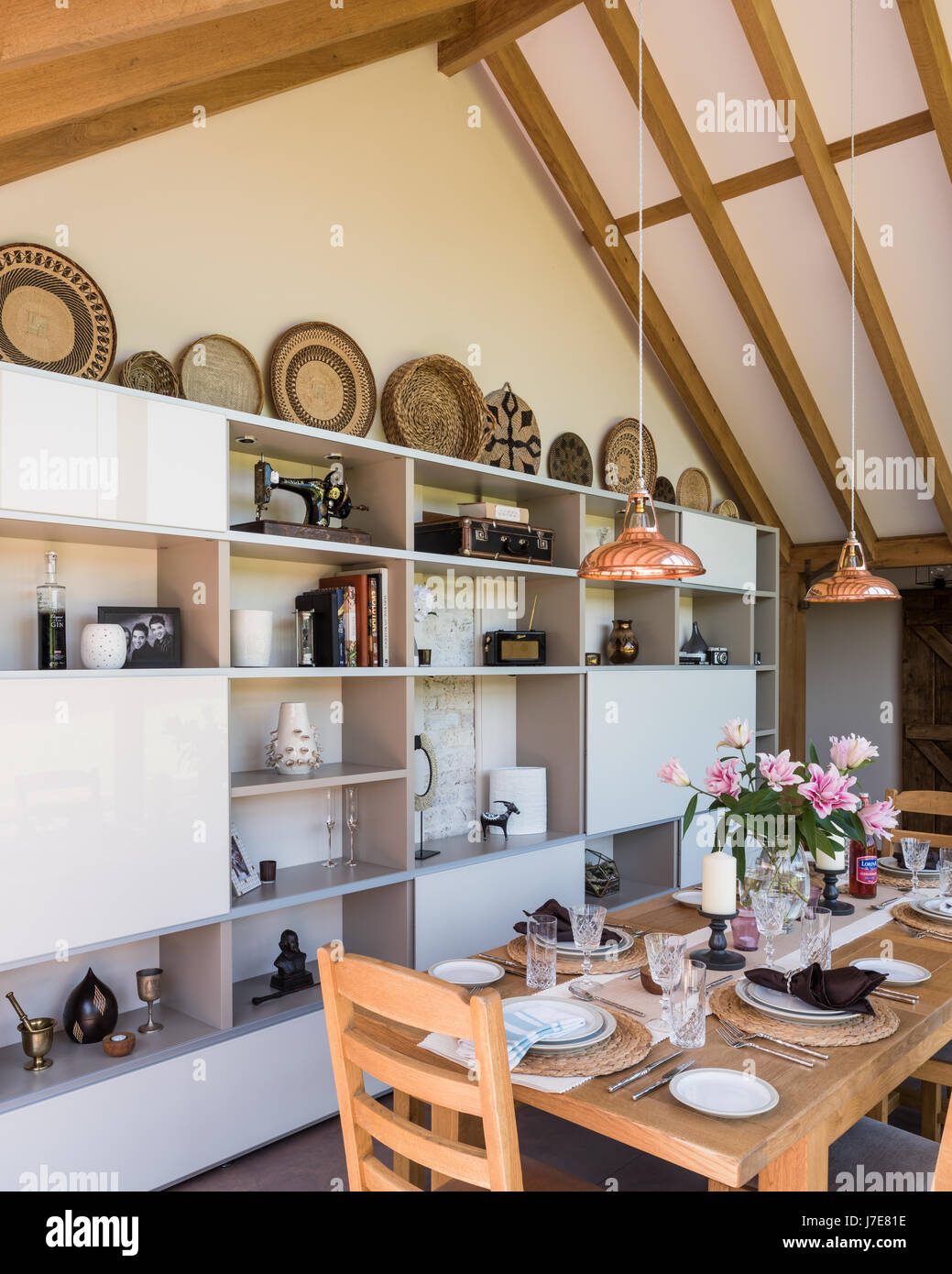 Vaulted oak-framed dining room with floor-to-ceiling windows. The table and chairs are from John Lewis and the coolicon insustrial copper pendant ligh Stock Photo