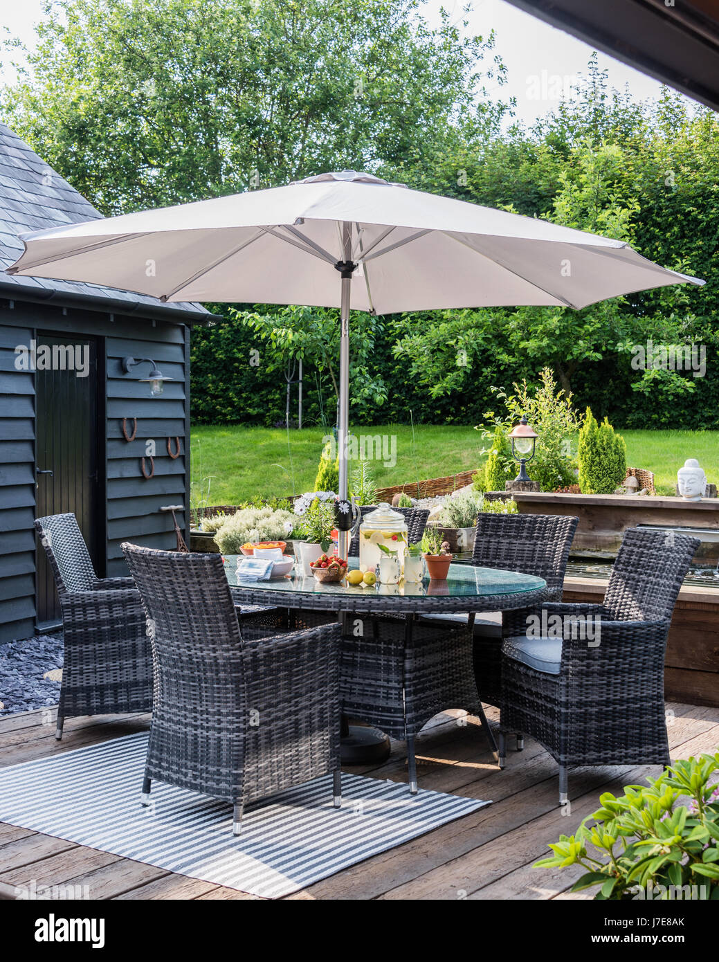 Outdoor furniture under parasol in elegant garden Stock Photo