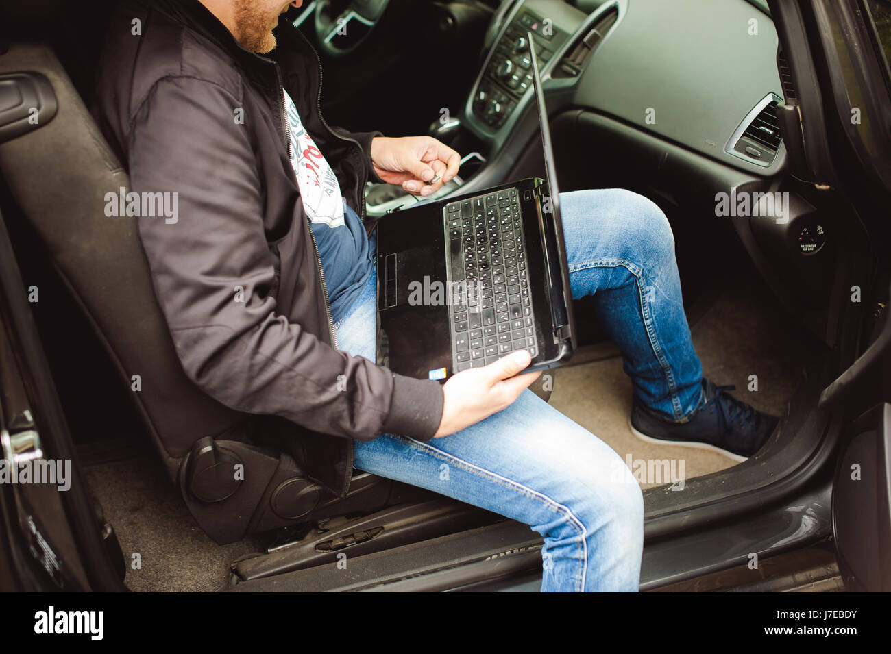 Professional man with a laptop in car tunes tuning control system