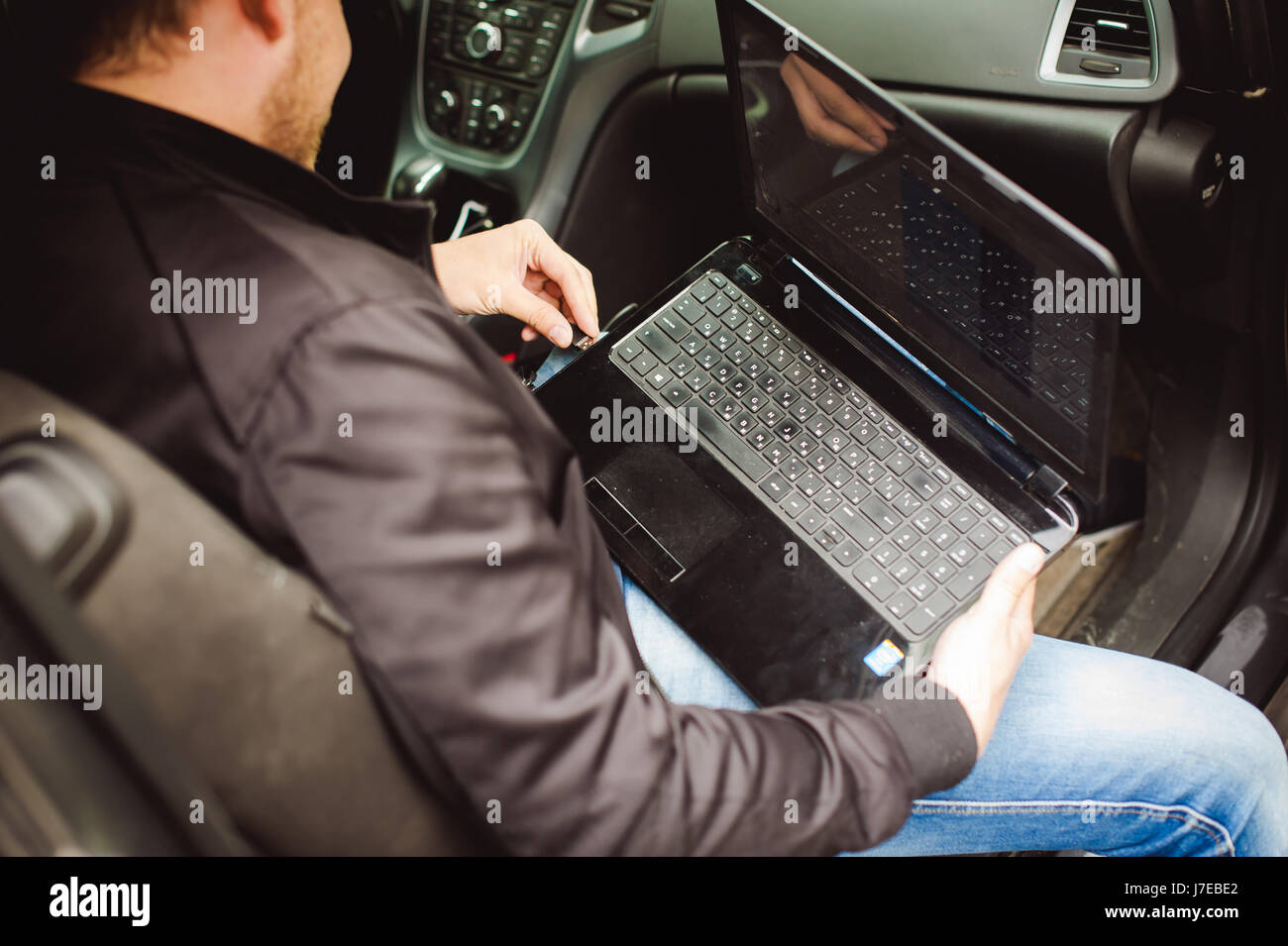 Professional man with a laptop in car tunes tuning control system