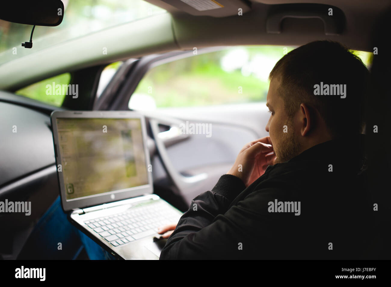 Professional man with a laptop in car tunes tuning control system