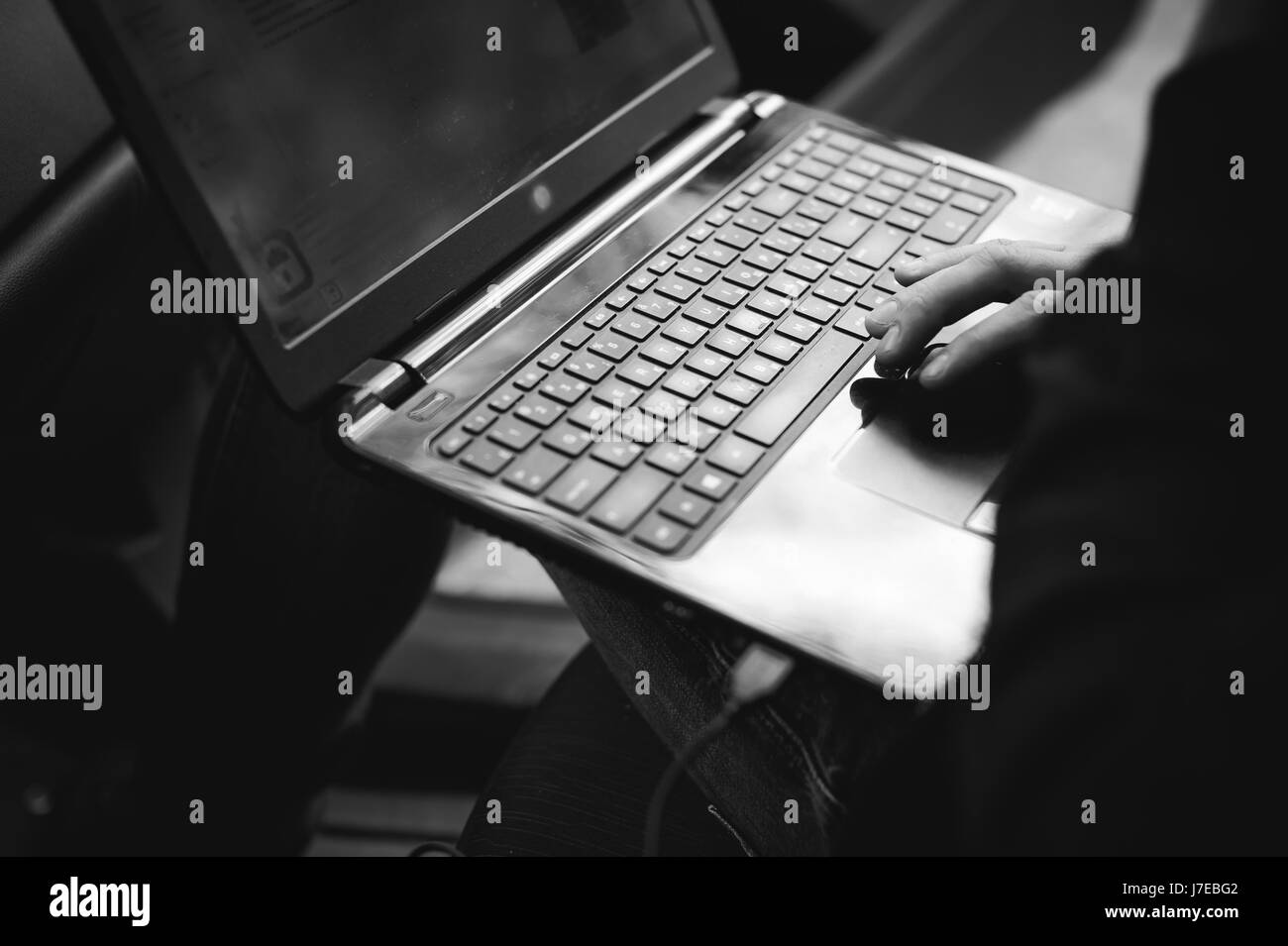 Professional man with a laptop in car tunes tuning control system, updating software, gaining access through to computer, sitting in cabin Stock Photo