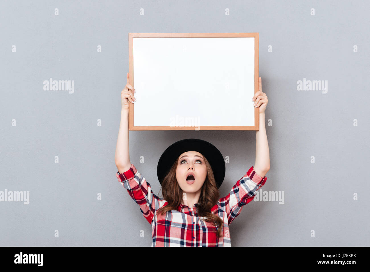 Image of shocked young lady standing over grey background with ...