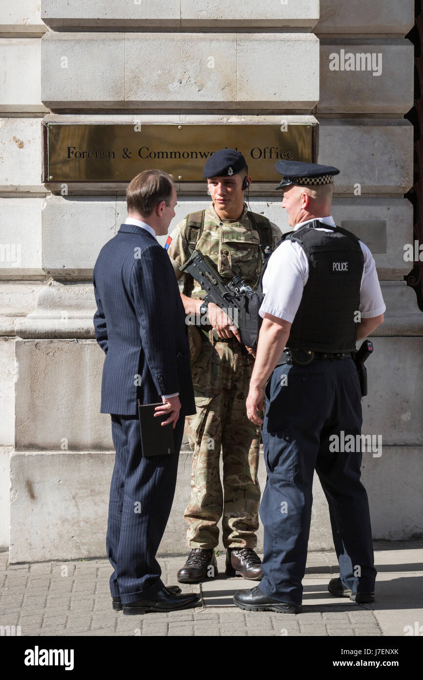 London, UK. 24 May 2017. An armed police officer and a soldier guard the Foreign & Commonwealth Office in Westminster and talk to a passer-by. Soldiers have been deployed to Westminster in the wake of the terrorist attack in Manchester.  Photo: Vibrant Pictures/Alamy Live News Stock Photo